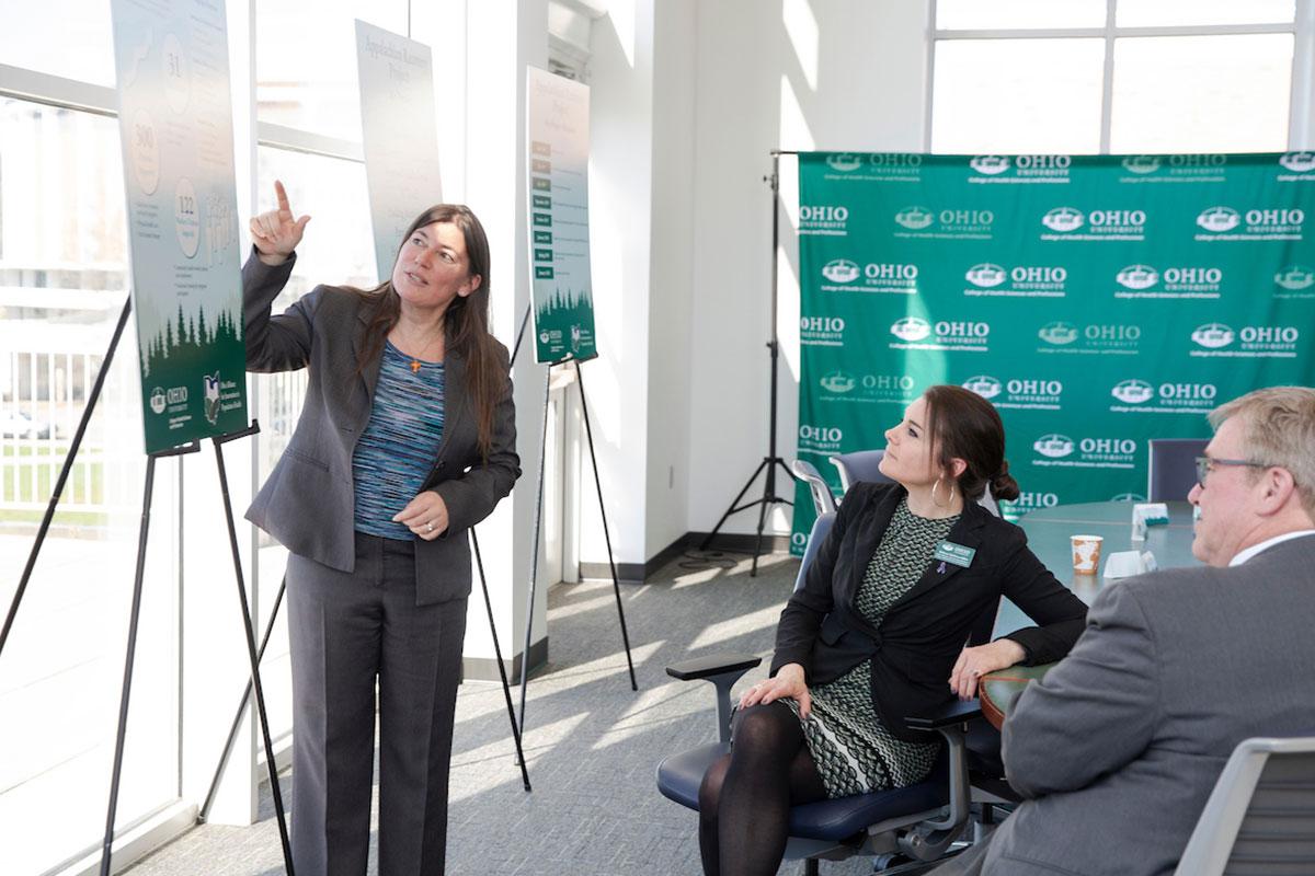 Person speaks in front of a poster with attendees listening