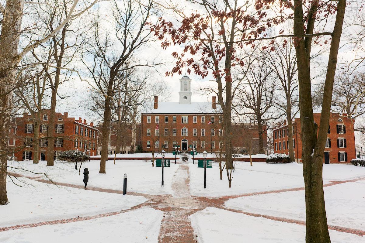 Cutler Hall surrounded by sidewalks and trees on College Green covered in snow