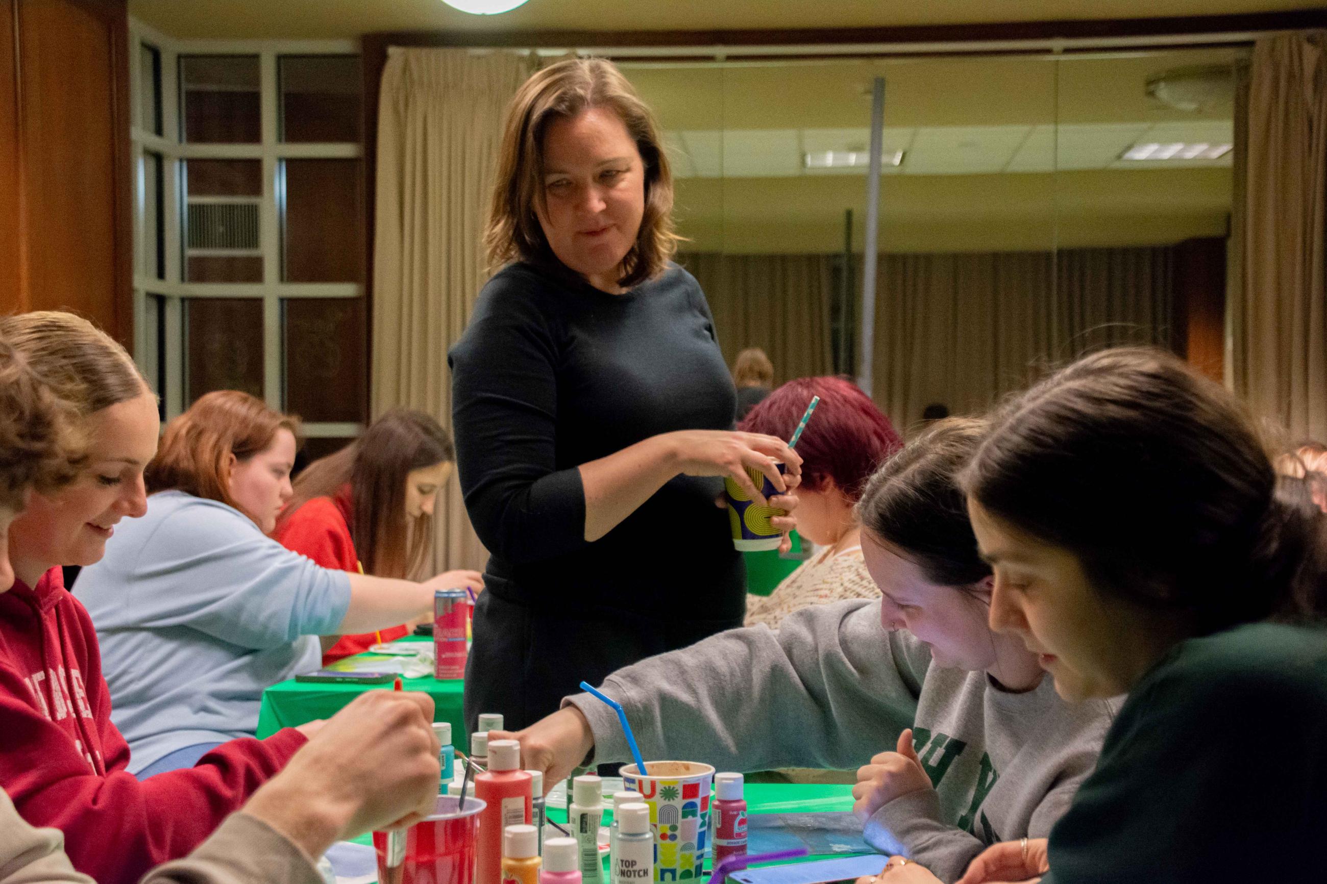 Sarah Green looking at student's canvases during a Paint n Sip