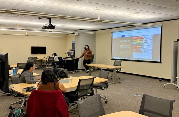 A group of people sitting in a room, staring at a screen