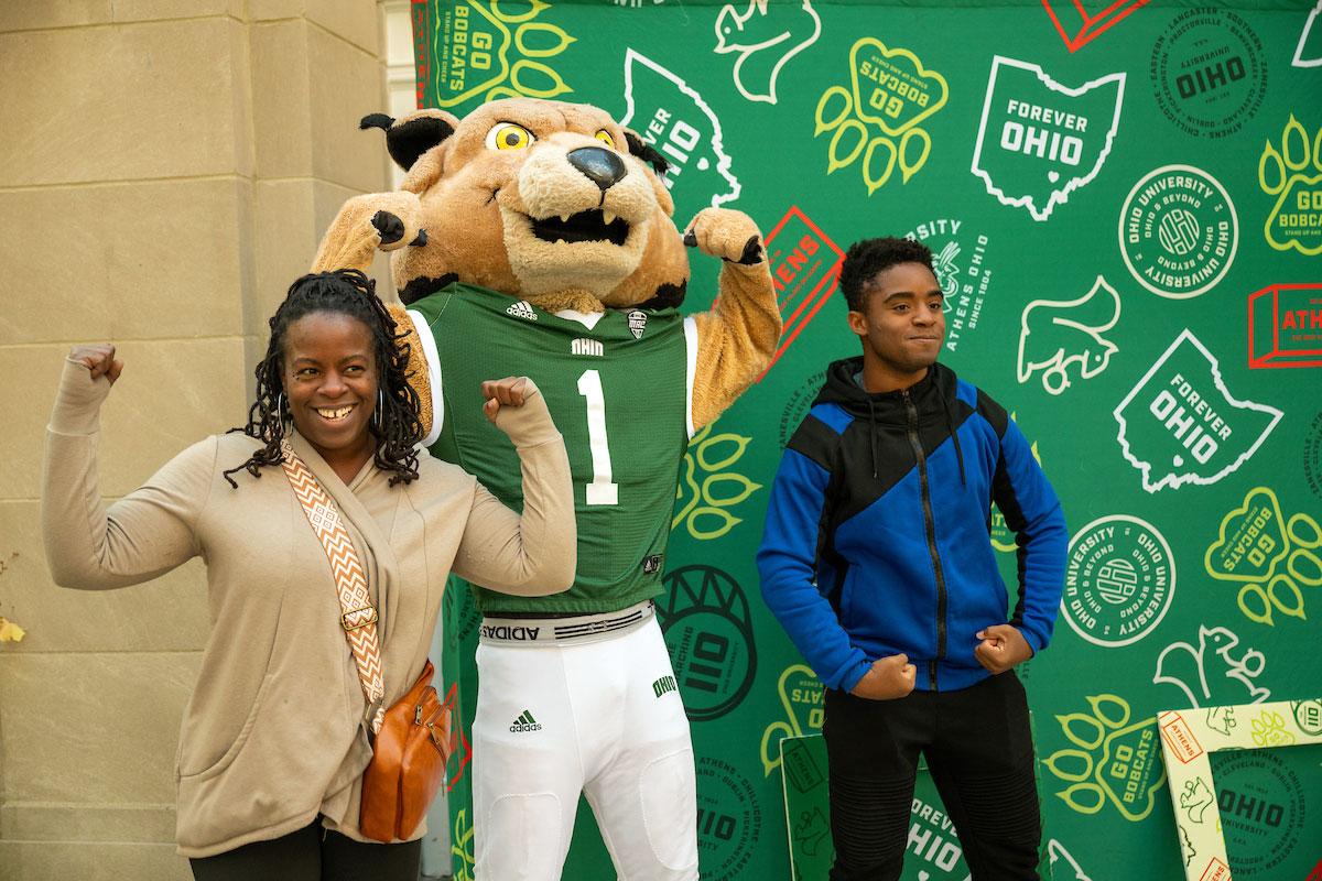 A student poses with his mom alongside OHIO mascot Rufus Bobcat