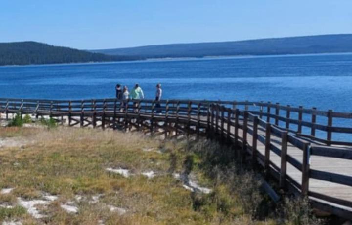 People walking on wooden walkway with water behind.