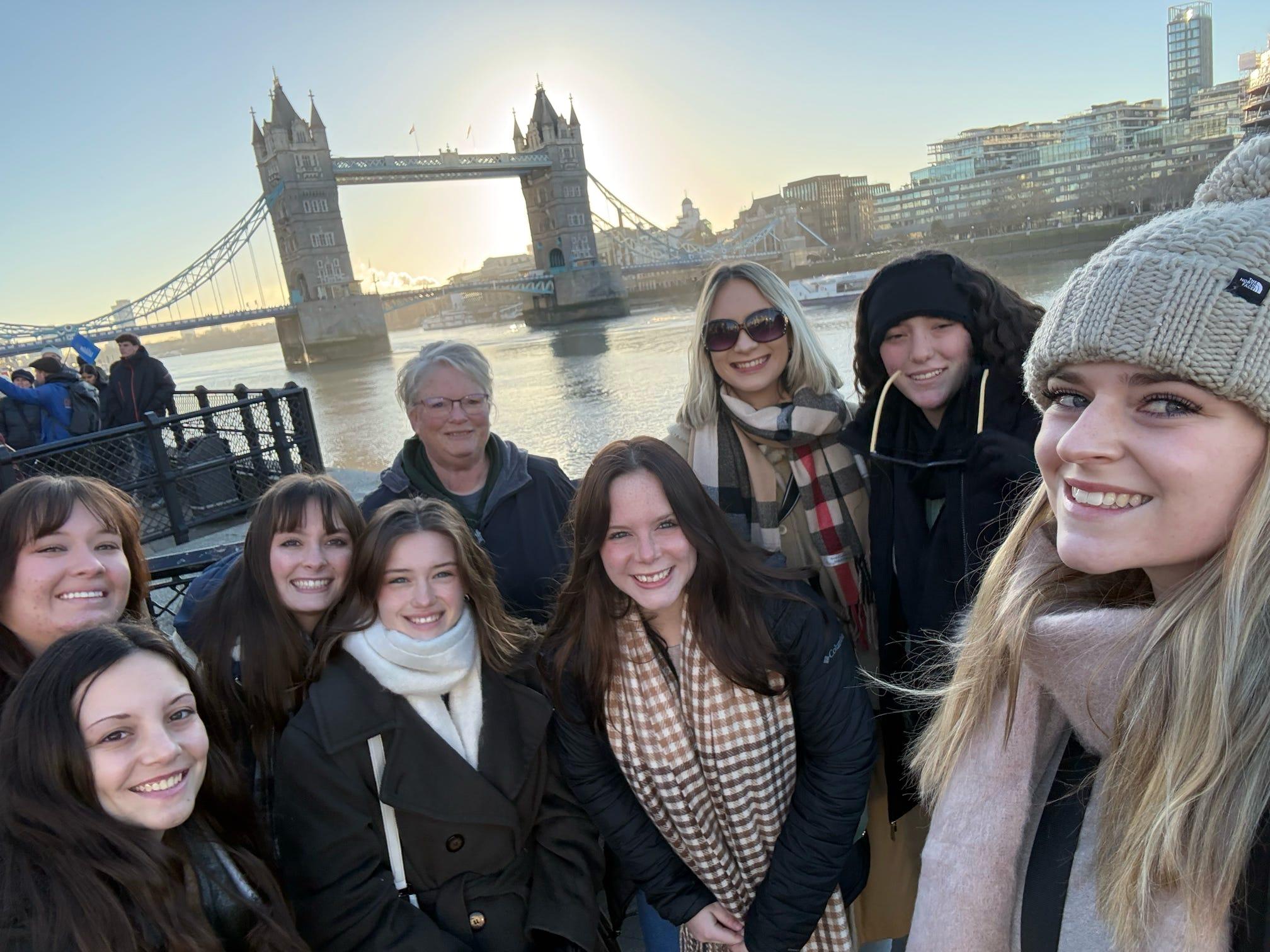 A group of Ohio University students and faculty stand in front of the Tower Bridge