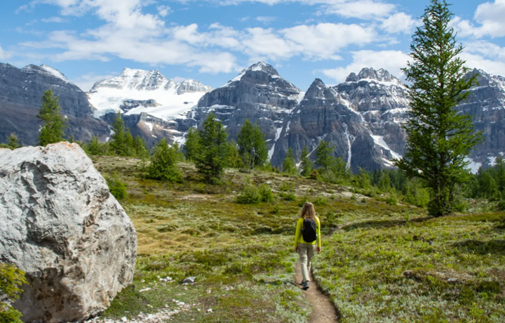 Person walking on path with Rockies in the background.