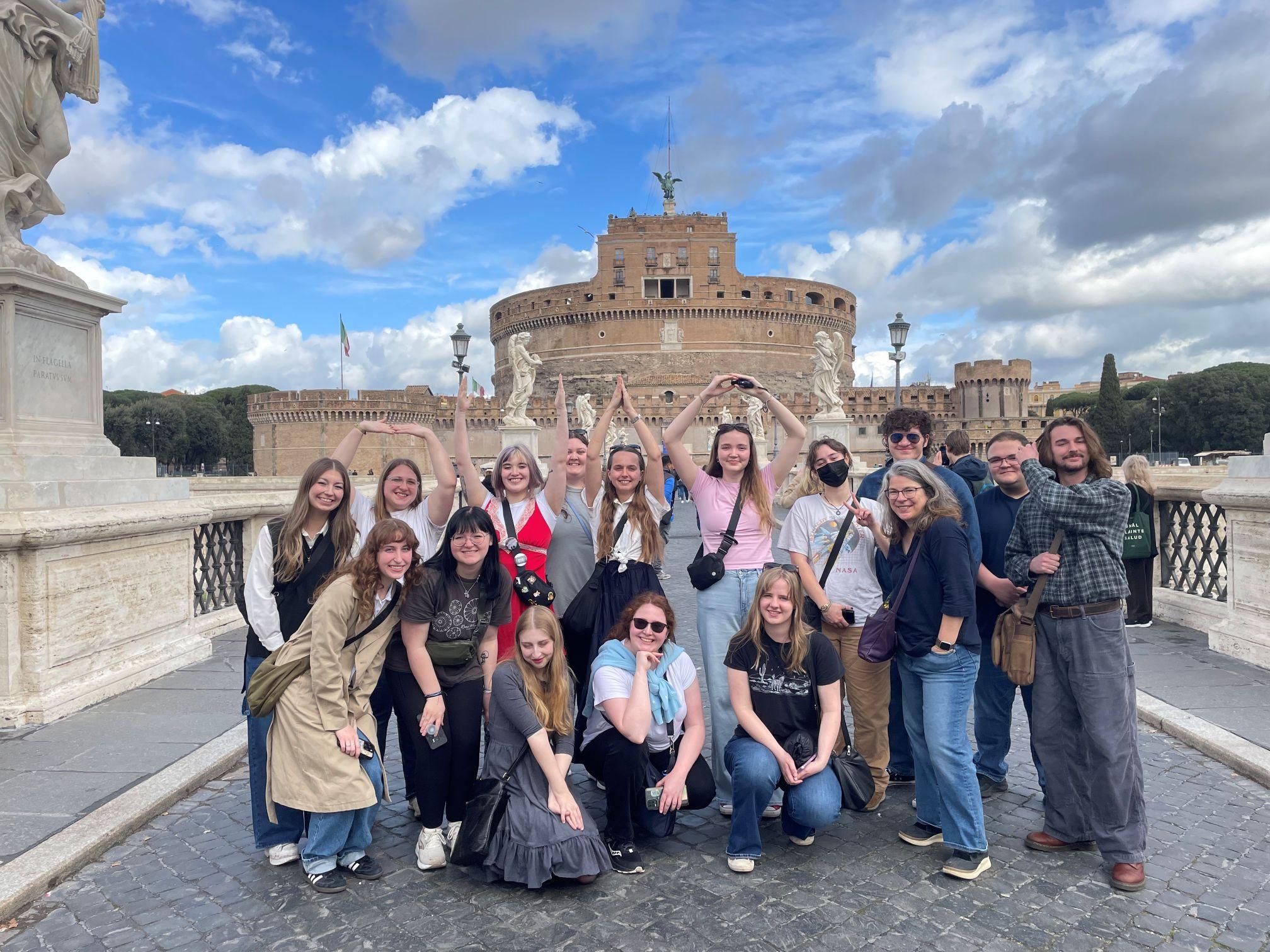A group of Ohio University Students and Faculty pose in front of a stone building with angelic statuesItaly