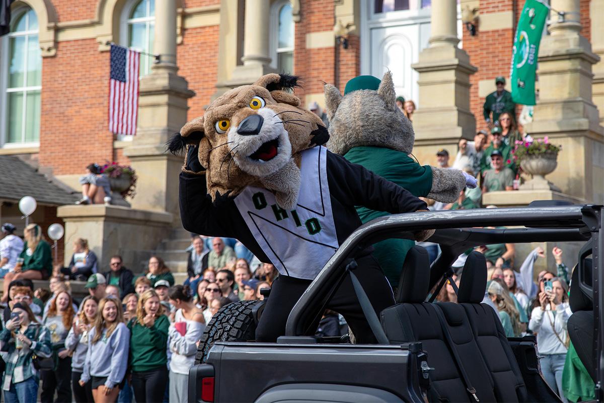 Rufus the Bobcat and Mr. Bobcat wave to onlookers from the back of a Jeep during Ohio University's 2025 Homecoming Parade.