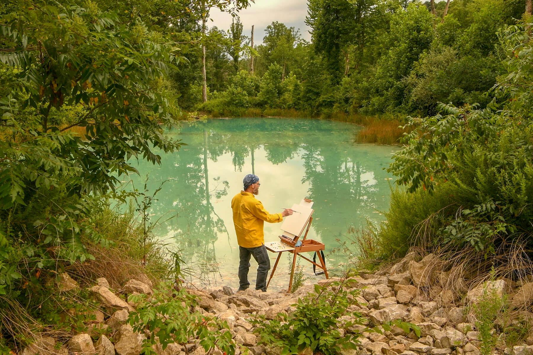 John Sabraw painting on a canvas by a pond