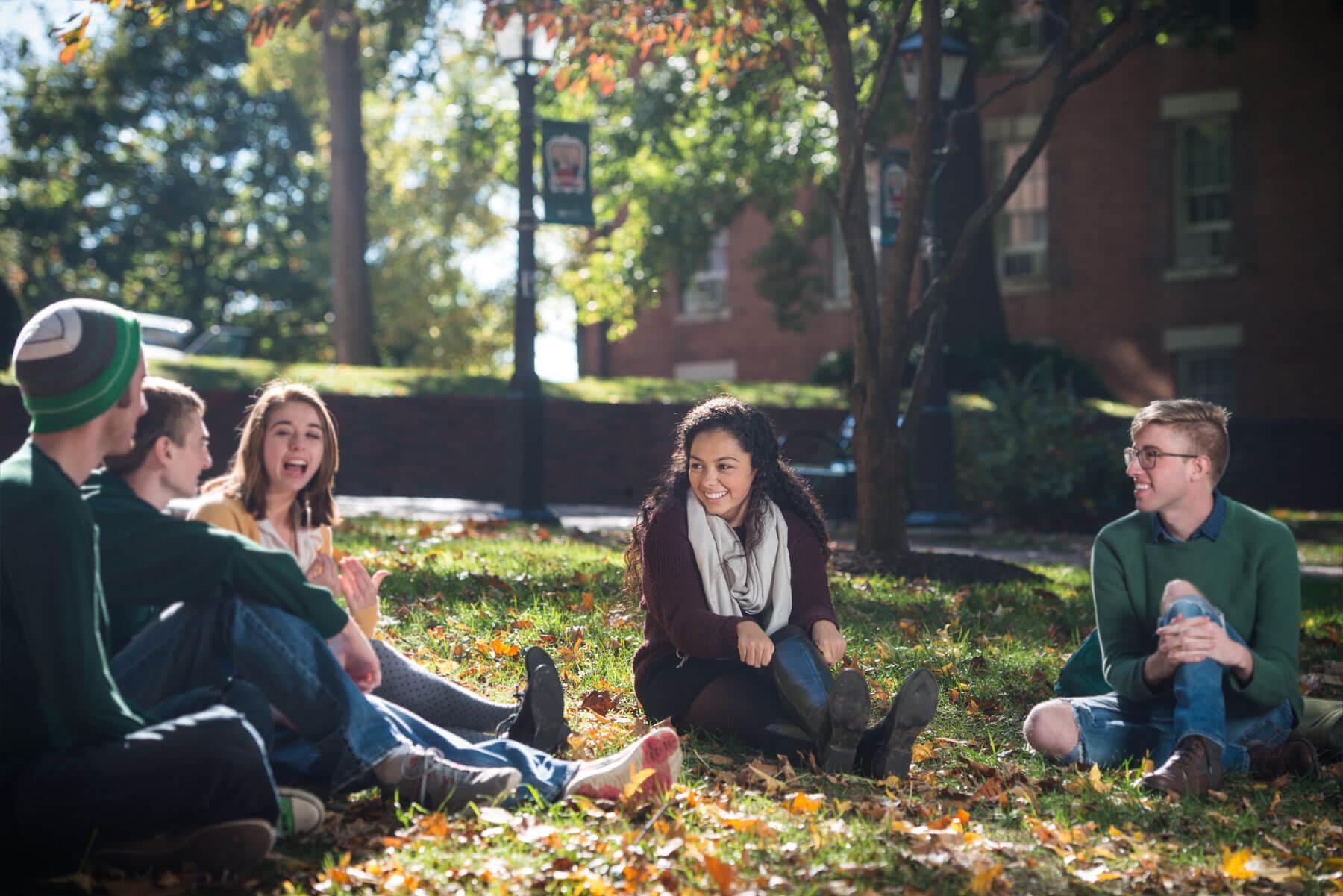 Students laugh and sit in a circle on College Green