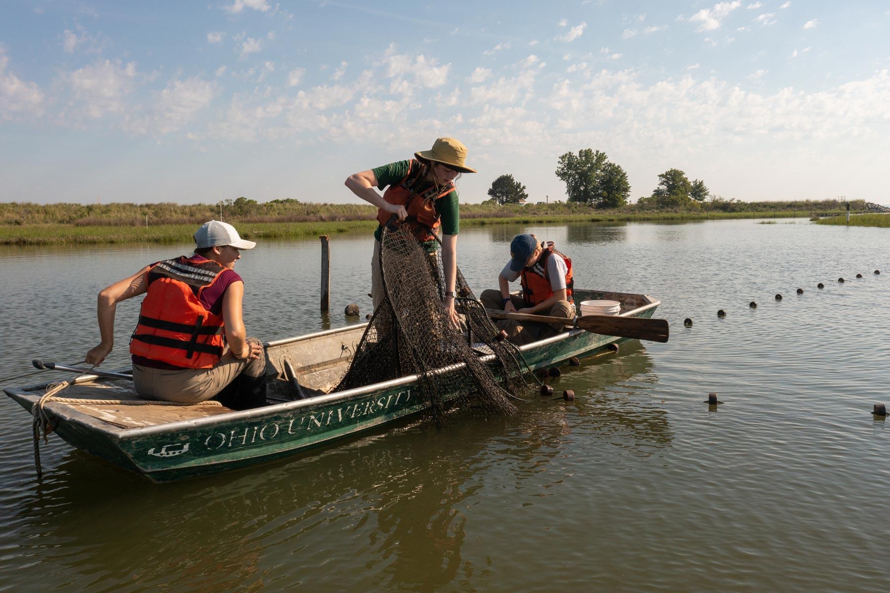 student pull up nets while in a boat on a local pond
