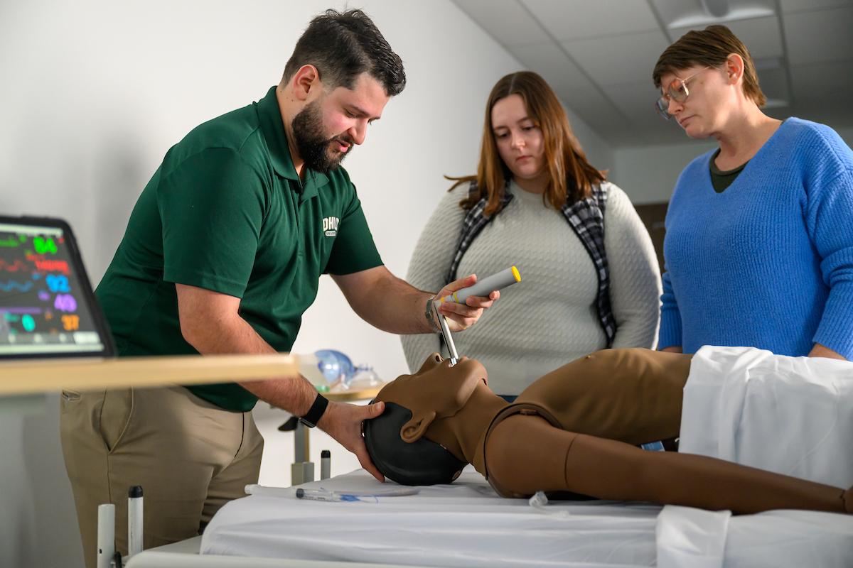 Health students watch a demonstration on a medical mannequin
