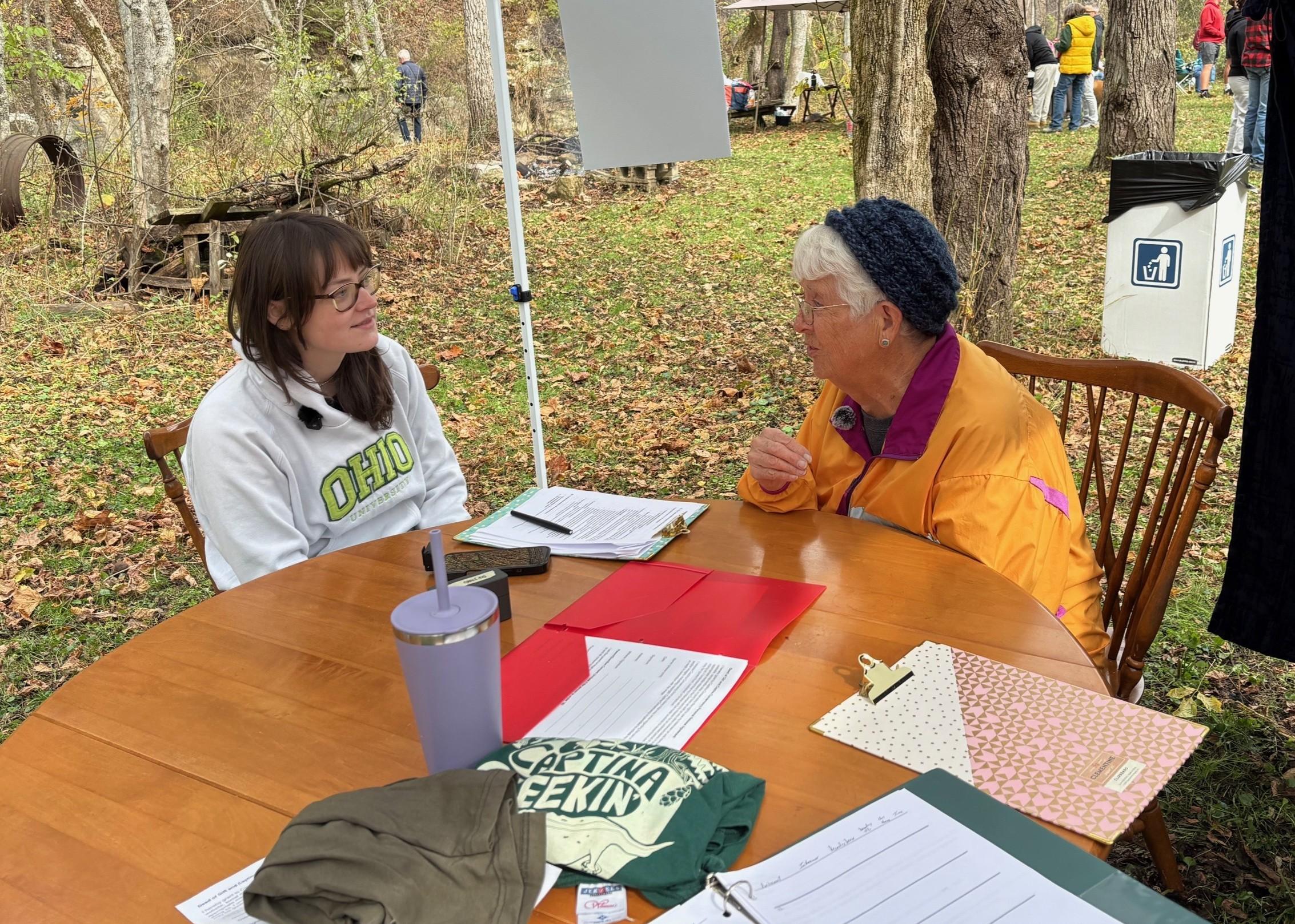 Amellia Woolard speaking to elderly woman wearing a yellow jacket
