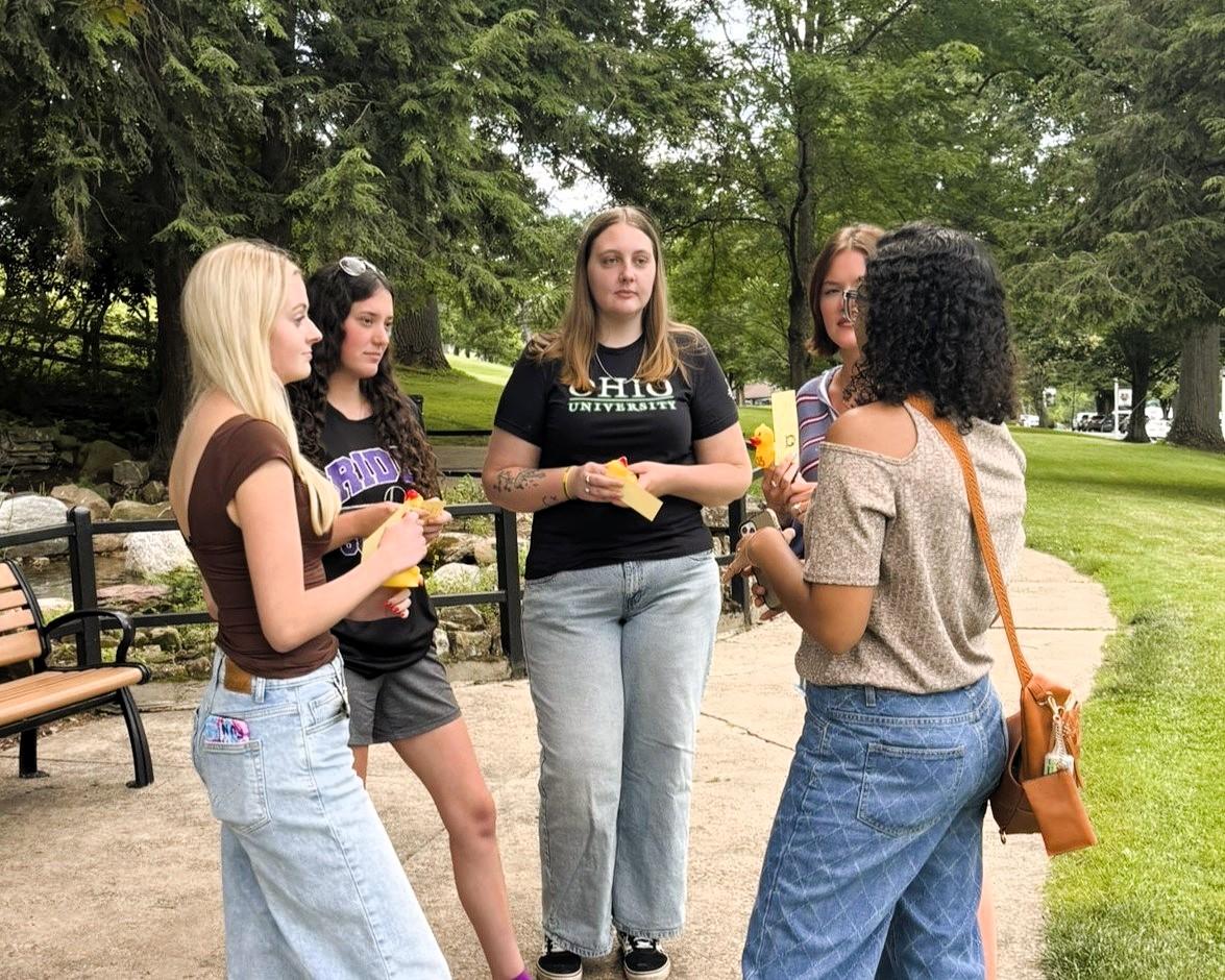 5 female students talking in a group outside on a sunny day in a park