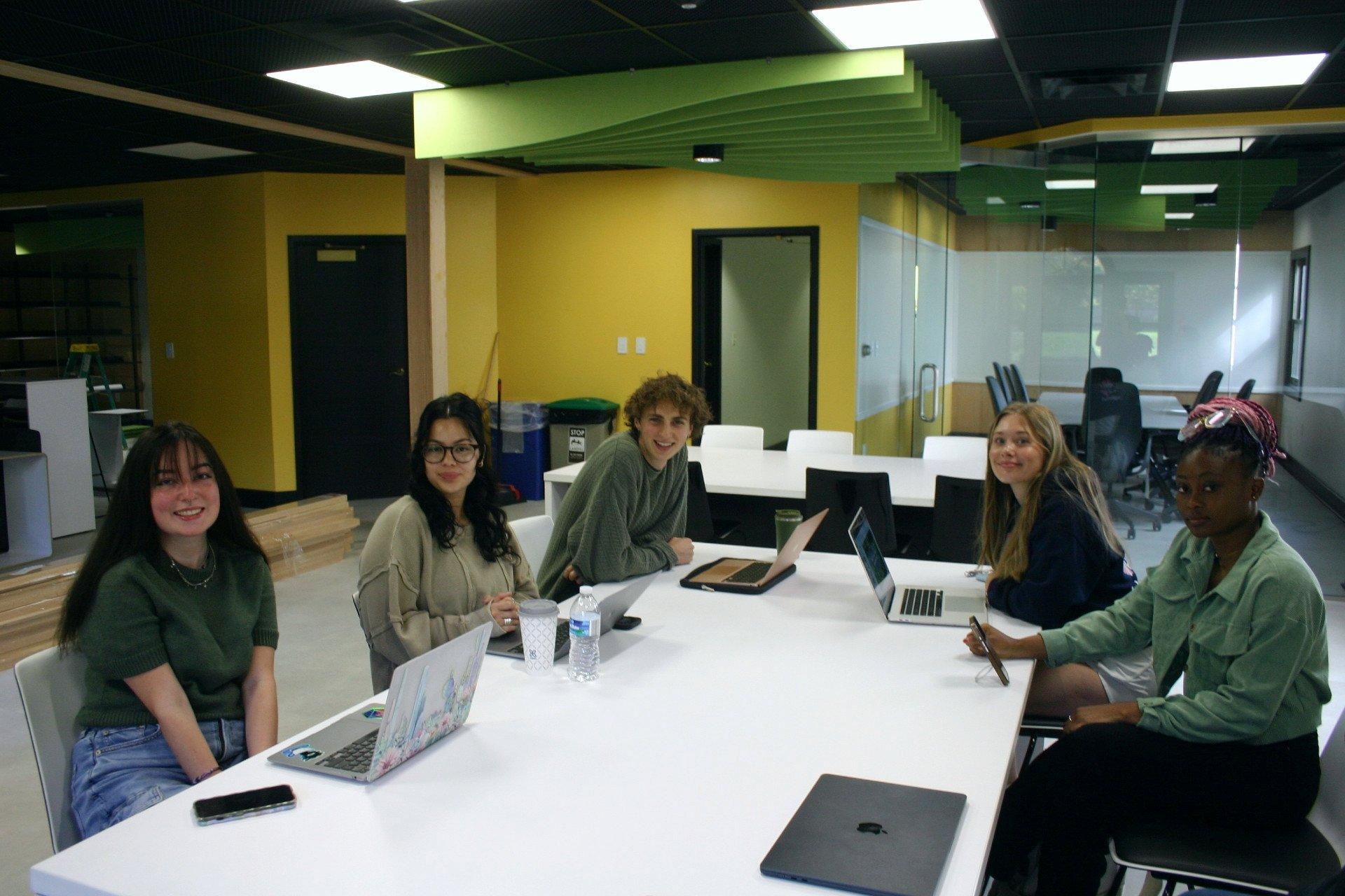 Students sit at a table working at the Next student-run advertising agency