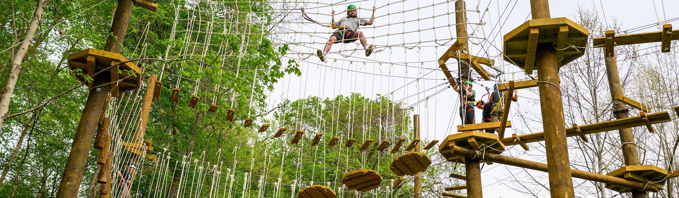 man tries to keep his balance on the ropes in challenge course