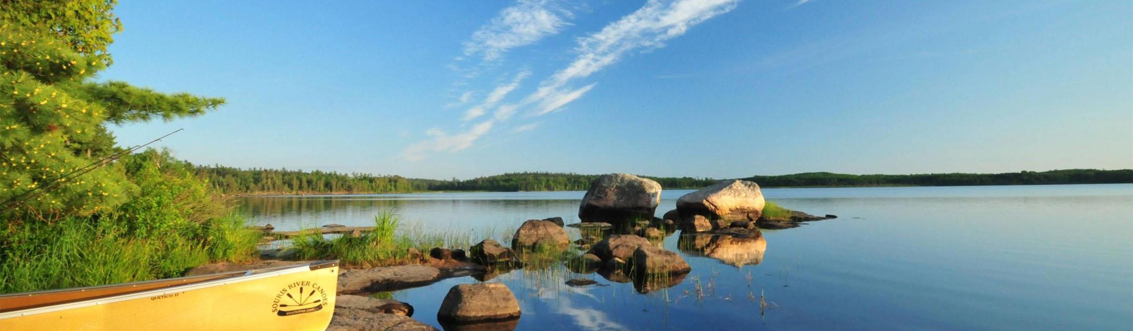 beautiful scenery of boundary waters with a boat in the foreground and blue skies and serene waters
