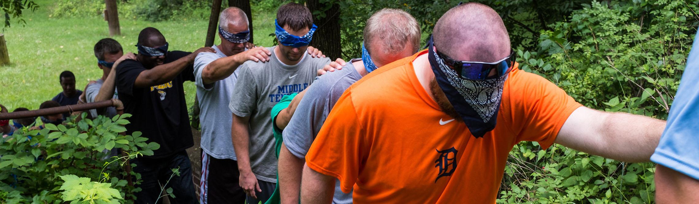 students participate in a Sherpa Walk activity during the outdoor challenge course