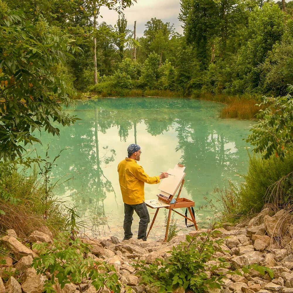 John Sabraw painting on a canvas by a pond