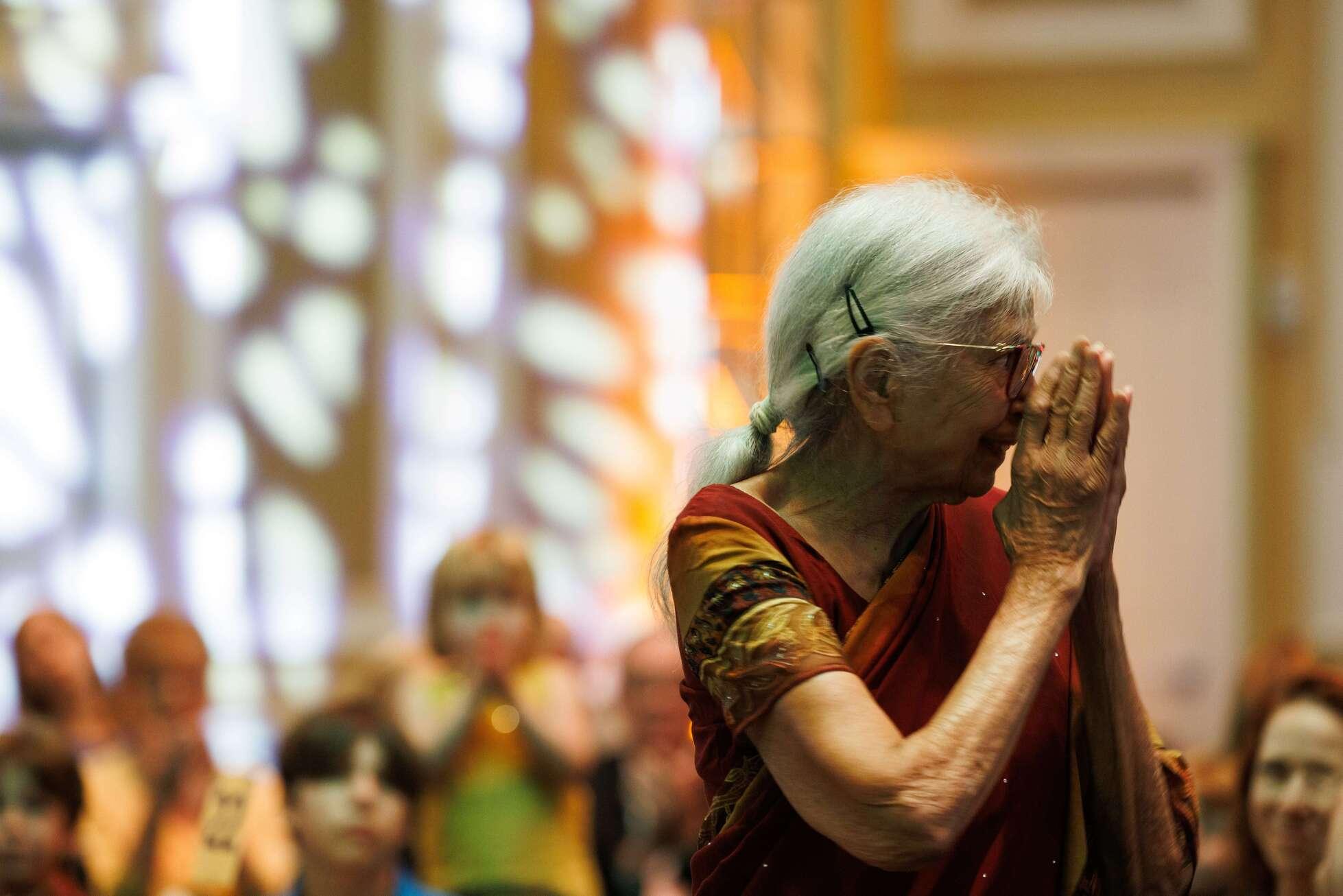 Dr. Sushila Gawnade standing with her hands up to her face with a crowd of Friends of India guests blurred in the background behind her