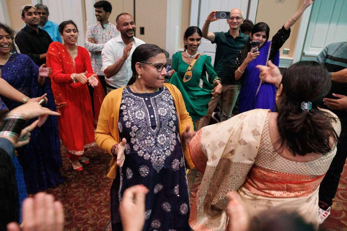Close-up of many attendees dancing wearing colorful clothes. Some are throwing their arms up, and others are dancing in the center