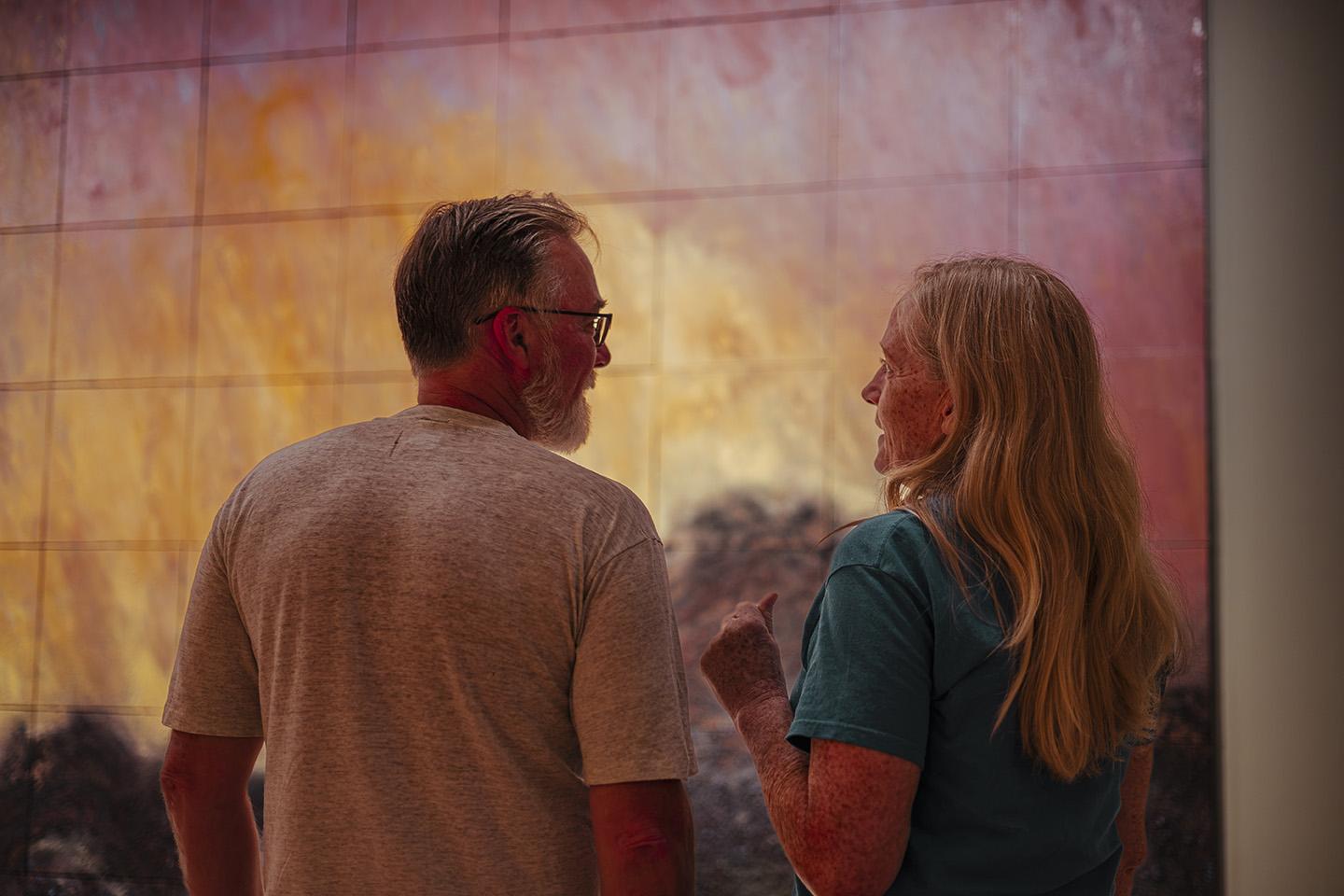 Two people standing in front of painting