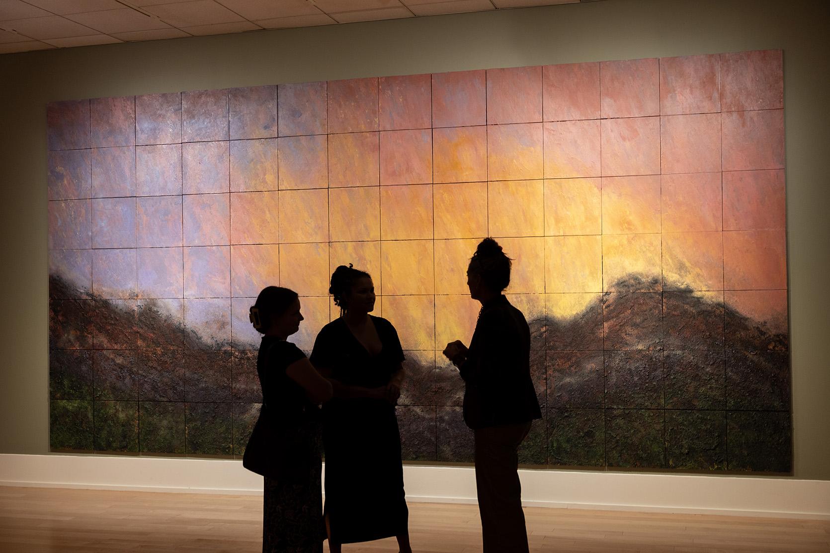 Group of people in silhouette in front of painting