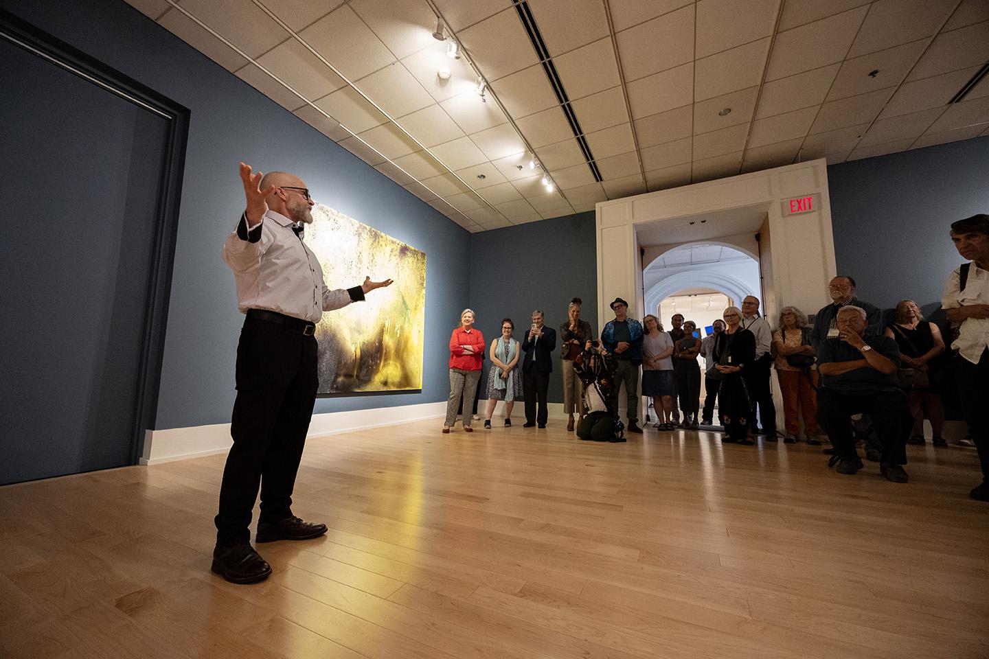 Artist addressing crowd in gallery reception