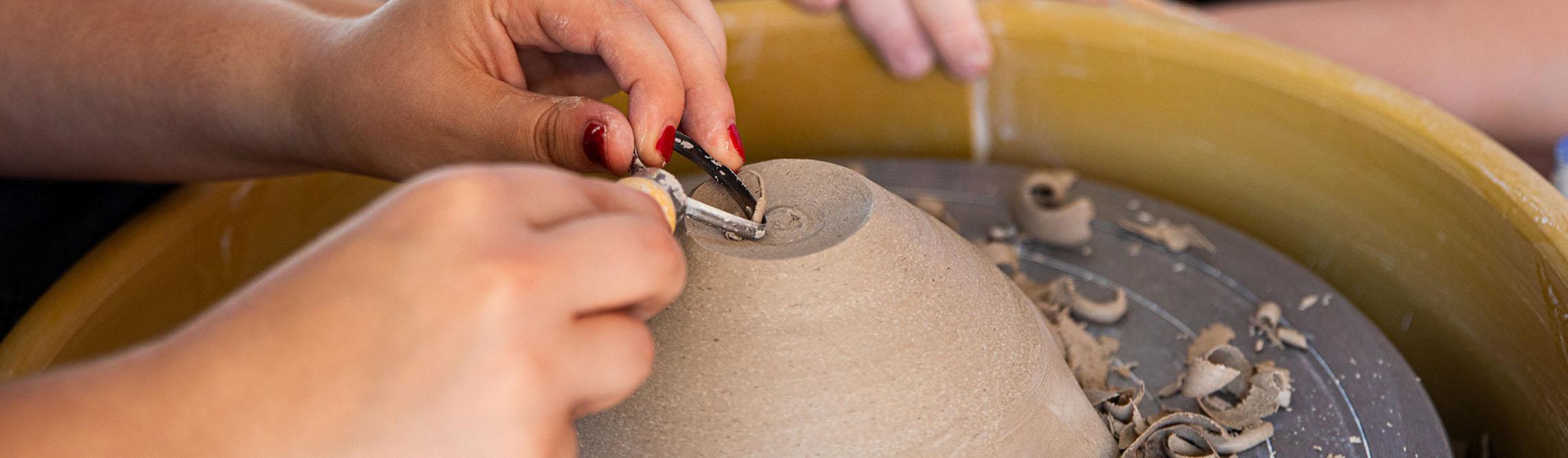 female hands working on a clay vase 