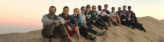 Global Health students and staff sitting on a sand dune