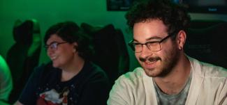Two students smile while playing video games in Ohio University's Esports facility