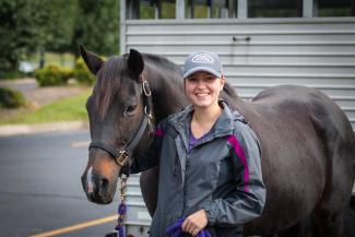 Student with horse in front of a horse trailer