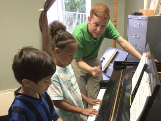An Ohio University student gives a private piano lesson to young children