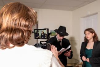 1 student is filming, 2 students are acting a film scene