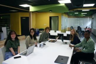 Students sit at a table working at the Next student-run advertising agency
