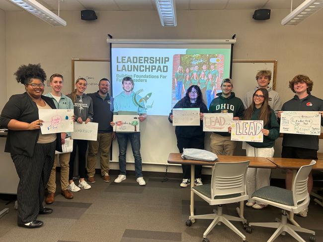 Students in the Leadership Launchpad hold up posters about leadership they've worked on