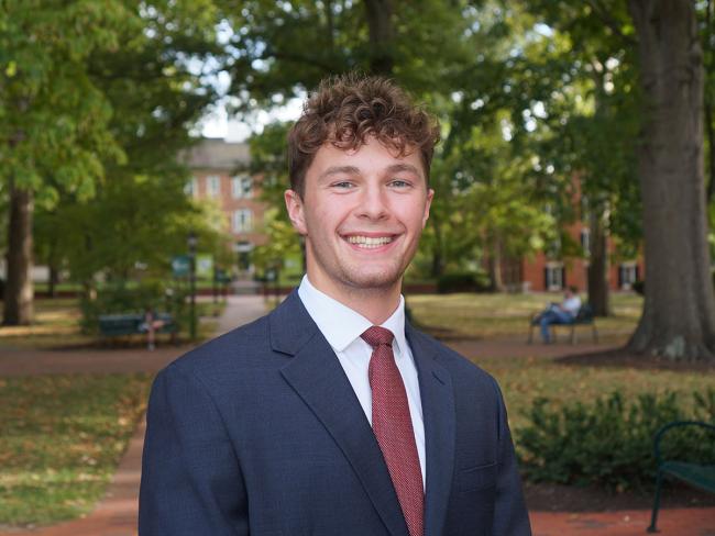 Student poses in a suit on College Green