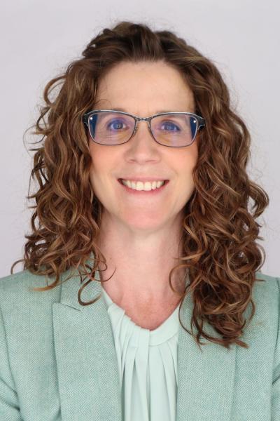 Head shot of Jennider Dillie in a green jacket with a white background. 