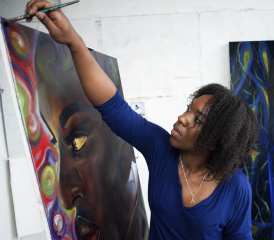 An Ohio University student paints a large portrait of a woman in the Seigfried Hall makerspace