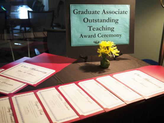Certificates for the Graduate Associate Outstanding Teaching Award line a table at the ceremony