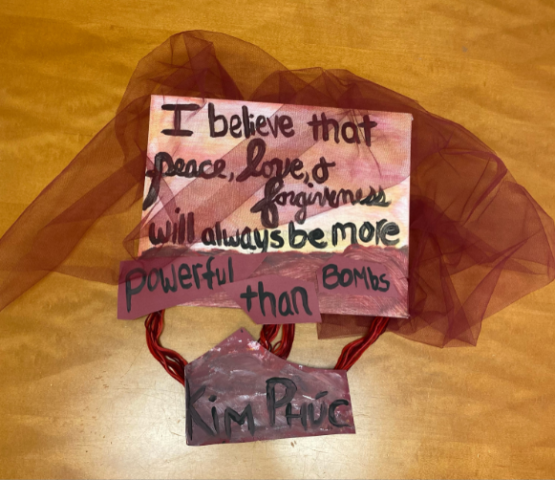 "I believe that peace, love, and forgiveness will always be more powerful than bombs" is written on a canvas underneath dark red gauze.