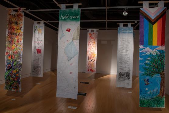 Banners hang in Trisolini Gallery, with imagery that includes the LGBTQ progress flag.
