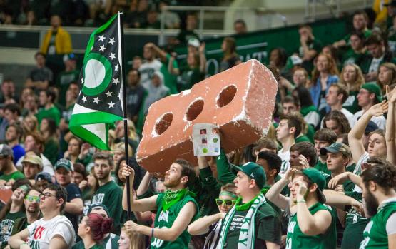 Ohio Bobcat student fans cheer and hold a giant foam brick at a basketball game