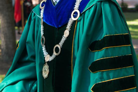 Close-up of Ohio University's presidential regalia, featuring a dark green cape with black velvet stripes, and a velvet blue hood.