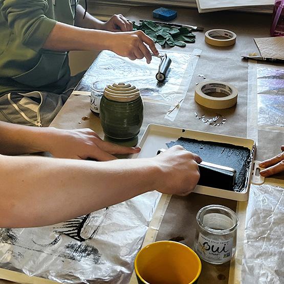 People at table using printmaking tools and ink to create art