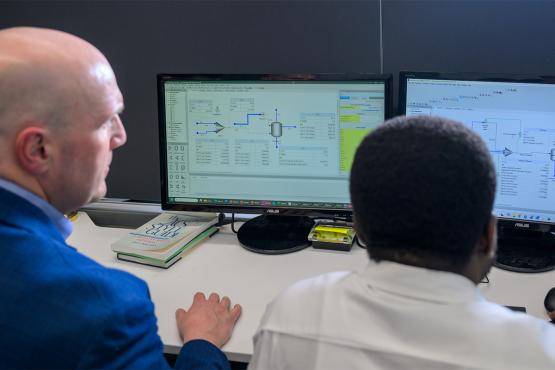 A faculty member and a student look at research on a computer together.