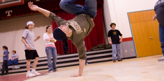 A person dancing hip hop while the class watches.