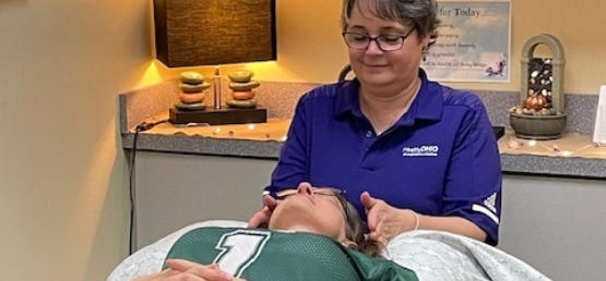 Reiki practitioner with hands near client's head.