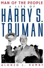 Black and white image of Truman smiling wearing a suit and holding hat up waving.