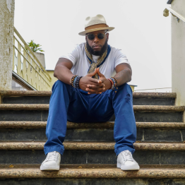 Talib Kweli sitting on stairs with hands clasped