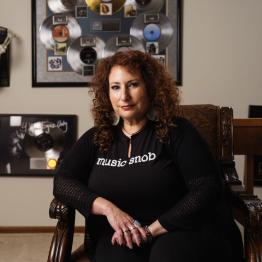 Deborah Mannis-Gardner sitting in chair with framed records in background
