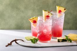 tropical cocktails topped with pineapple and cherries